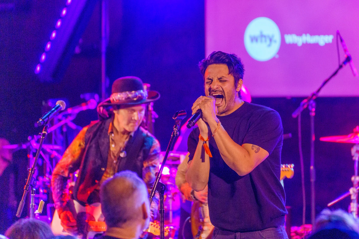 Singer performing on stage with a band during a WhyHunger event.